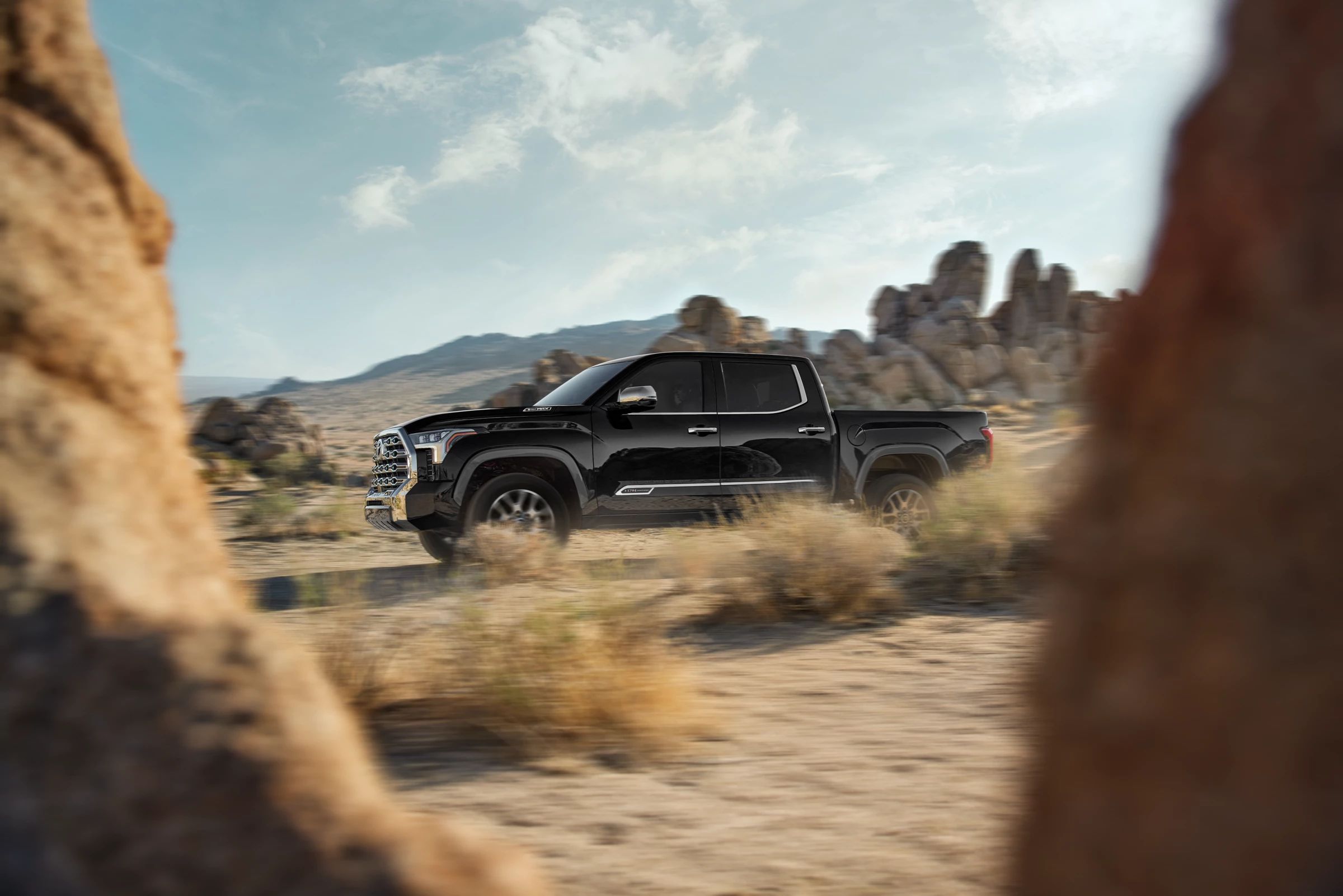 Black Toyota Tundra driving through desert rock country at golden hour